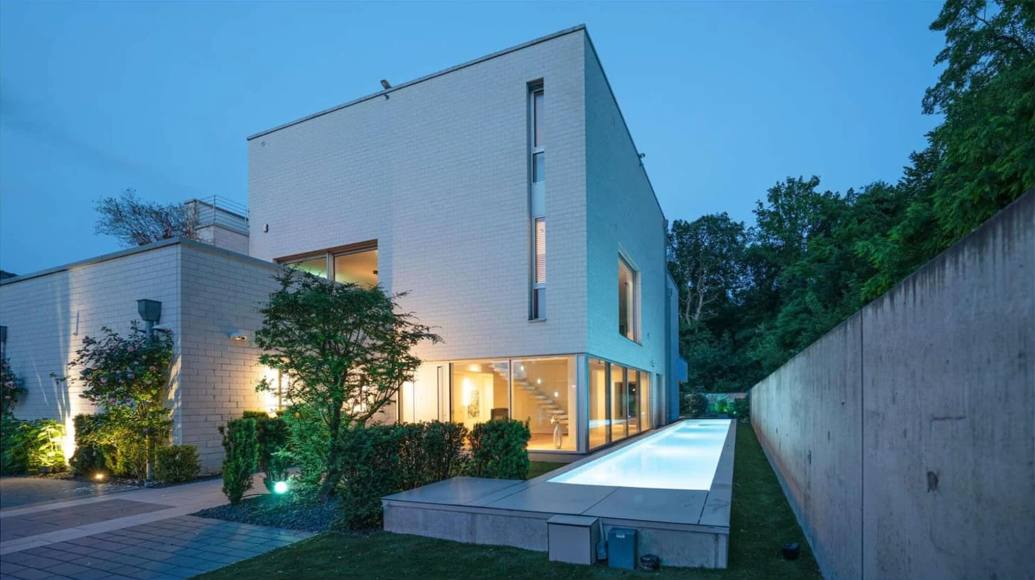 Vista completa della villa illuminata con piscina esterna luminosa di notte